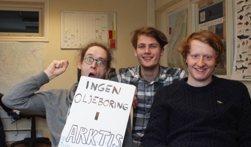 Arjo, Olav og Bendik smiler i kamera. Arjo holder en knytteneve i været og en håndplakat med teksten "Ingen oljeboring i Arktis"